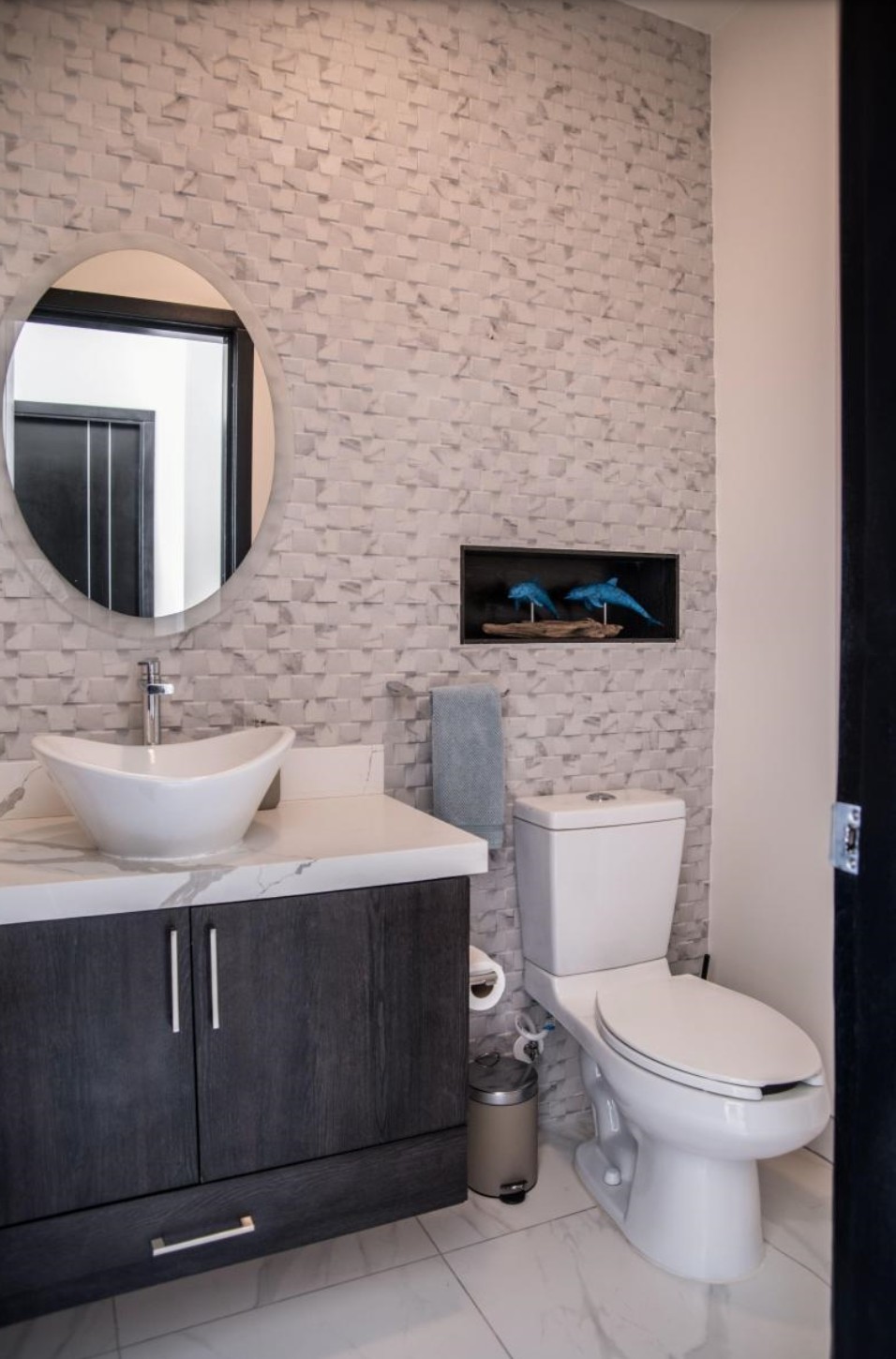 Half bathroom with textured stone wall and round mirror