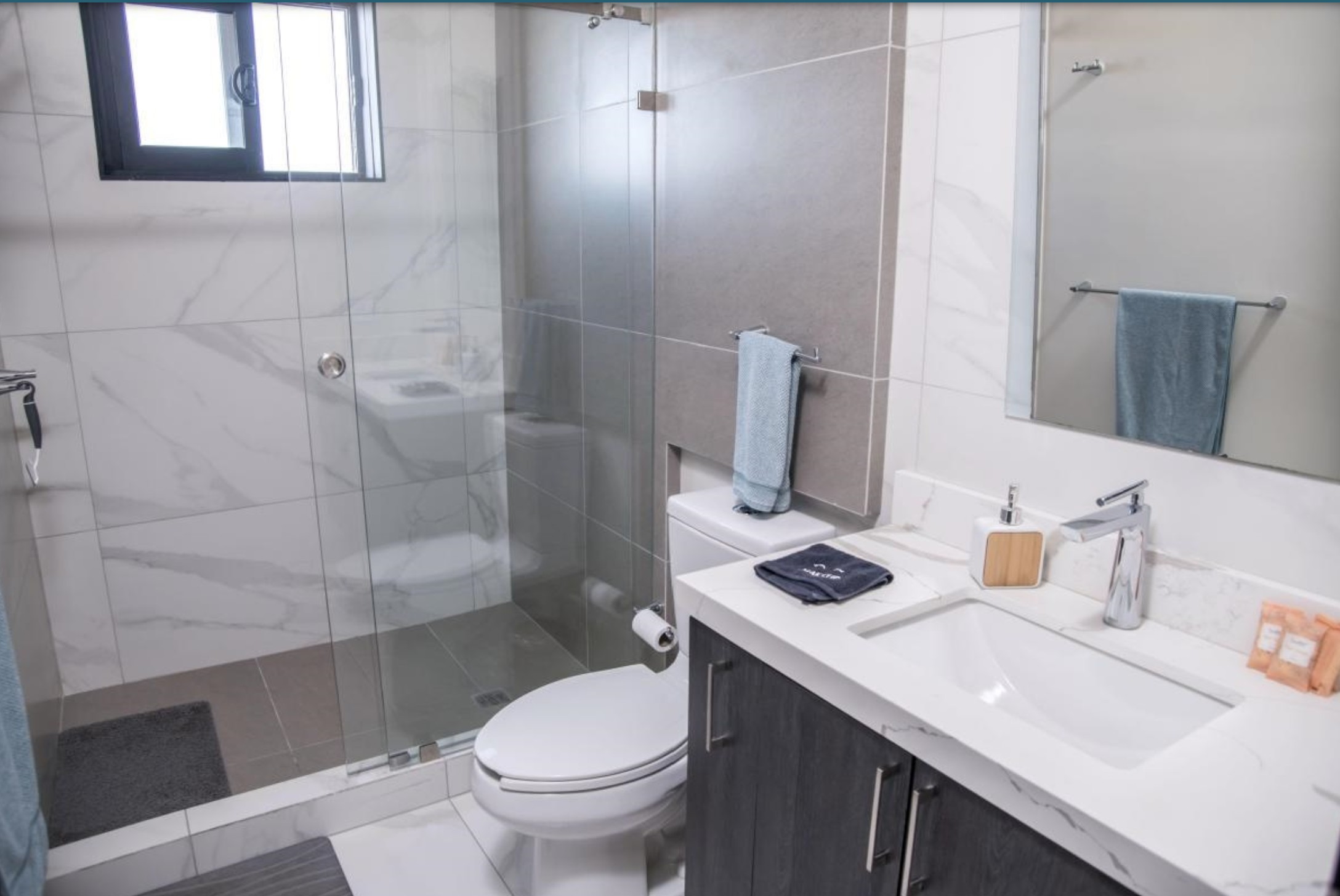 Second full bathroom with glass shower and white vanity